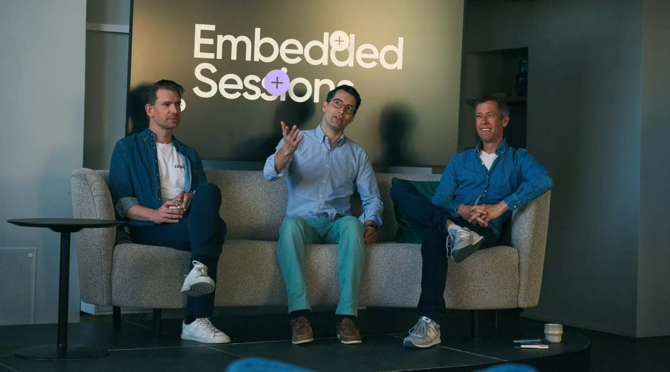 Three people seated on stage under an "Embedded Sessions" logo
